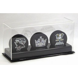 Eine gebogene klaRe AcRyldecke, die eine Basis bedeckt, die ein Foto sowie 3 Pucks gRoß hält