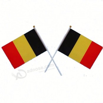 mão pequena do pólo plástico que acena a bandeira de Bélgica para aplaudir