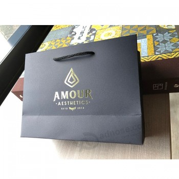Sac en papier imprimé logo doré noir mat de luxe avec poignées en corde pour l’emballage des vêtements